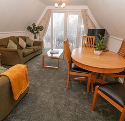 A living room with sofas coffee table dining table with chairs and plants at Brookside in Honicombe Manor near Gunnislake