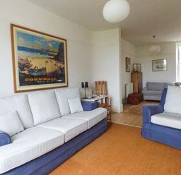 A living room with blue and white sofas a large wall poster and wooden furniture at Sandy Bank in Rhosneigr
