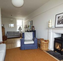 A living room with armchairs a fireplace a basket and a sofa at Sandy Bank in Rhosneigr