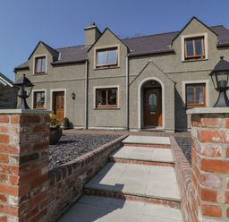 The front entrance of a stone house with stairs and brick pillars with lanterns at Caer Moel in Caernarfon