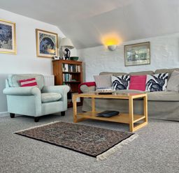 A living room with a sofa armchair coffee table rug and framed pictures on the wall at The Boat House in Golant near Tywardreath