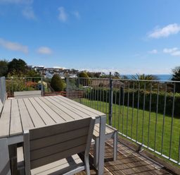 An outdoor area with a table and chairs overlooking the ocean at Treverrion in Gorran Haven