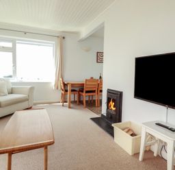 A living room with a sofa and dining area at Treverrion in Gorran Haven