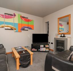A living room with a couch, coffee table, and television at Fortunatus in Whitby
