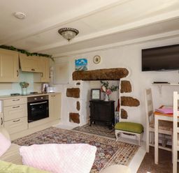 A kitchen with cabinets and a fireplace at Longview Cottage in Penwithick neat St Austell