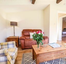 A living room with a sofa, table, and lamp at Snowdrop in Saltburn-by-the-Sea