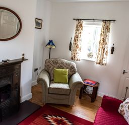 A sitting room with an armchair, sofa, fireplace, wall mirror, and window at Anvil Lodge in Goulceby near Louth