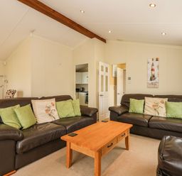 A living room with two leather sofas a wooden coffee table and cushions at Jolie in Hunstanton