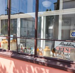 A window display with ceramic jugs bottles a dog figurine and a sign at The Merchant's Store in Kilrush Country Clare