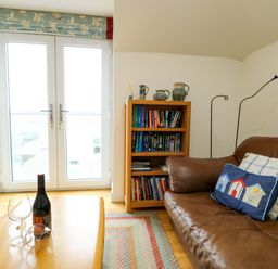 A living room with a bookshelf and a sofa at Maelog, 14 Tides Reach Rhosneigr
