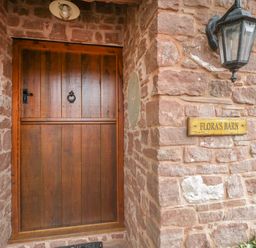 A wooden door on a stone wall with a mailbox and a lantern at Floras Barn in Crowcombe