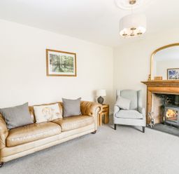 A living room with a leather sofa armchair fireplace and a large mirror at Viaduct House in Lydbrook
