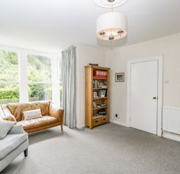 A living room with a leather sofa a fabric armchair a bookshelf and a door at Viaduct House in Lydbrook