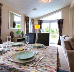 A dining room with a table set for meals and a sofa at Cheri in Southerness