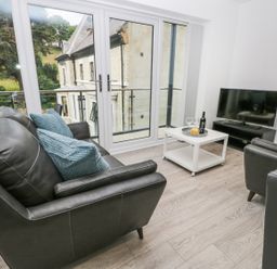 A living room with two black sofas a white coffee table and a TV at The Office Gardens Apartment 2 in Whitby