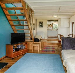 A living room with wooden stairs a television a sofa and a dining area at Pen Y Graig in Talysarn