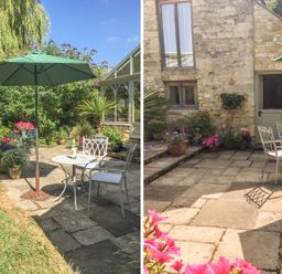An outdoor patio area with metal chairs and tables under a green umbrella surrounded by plants and flowers at The Old Cider House in Prestbury near Cheltenham
