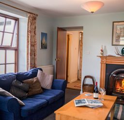 A living room with a blue sofa and wooden coffee table in front of a fireplace at Shepherds Retreat in Gortin