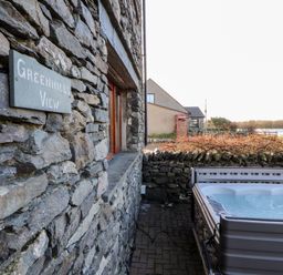 A stone building with a sign reading greenhills view and a hot tub on a paved area at Green Hills Farm in Ulverston
