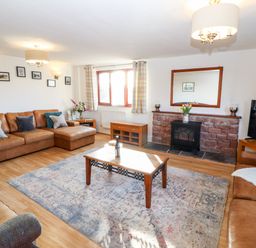 A living room with brown leather sofas a wooden coffee table a rug a TV and a fireplace at Green Hills Farm in Ulverston