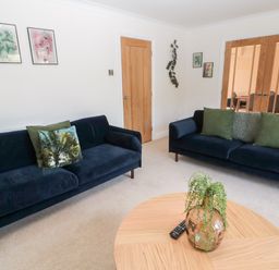 A living room with two dark sofas and a round wooden coffee table with a plant at The Croft in Longhoughton near Alnwick