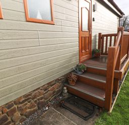 An entrance door with wooden steps and railings with potted plants on the porch at The Retreat in Wisemans Bridge near Saundersfoot