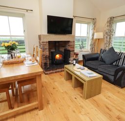 A living room with a fireplace and dining table at Bank Top Cottage in Embleton
