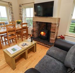 A living room with a fireplace and dining area at Bank Top Cottage in Embleton