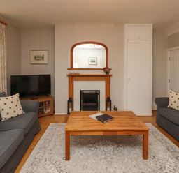 A living room with two grey sofas a wooden coffee table a fireplace and a television at Jasmine Cottage in Lesbury near Alnmouth