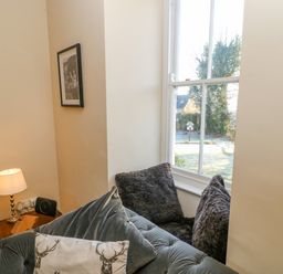 A seating area with cushions next to a window and a small table with a lamp at East Farmhouse Cottage in Humshaugh near Hexham