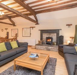 A living room with two gray sofas green cushions a wooden coffee table and a fireplace at Riven Oak in Lyth Valley near Levens