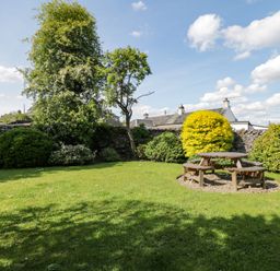A garden with green grass bushes and a wooden picnic table at Riven Oak in Lyth Valley near Levens