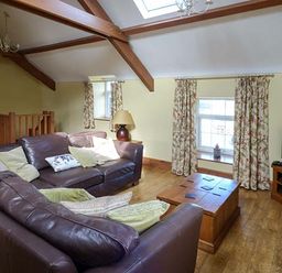 A living room with brown leather sofas wooden coffee table television and floral curtains at Bran Goesgoch in Holyhead