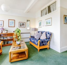 A living room with two blue floral armchairs a wooden coffee table with a plant and a sideboard with books and decorations at Clooneavin Apartment 3 Lynmouth near Lynton