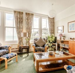 A living room with armchairs a coffee table plants and large windows overlooking the sea at Clooneavin Apartment 3 Lynmouth near Lynton