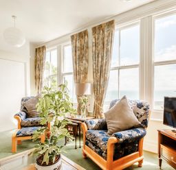 A living room with patterned armchairs a plant and a television at Clooneavin Apartment 3 in Lynmouth near Lynton