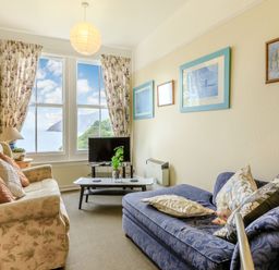 A living room with two sofas a coffee table a television and a large window with ocean view at Clooneavin Apartment 5 in Lynmouth near Lynton