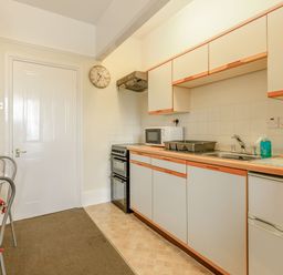 A kitchen with cabinets stove microwave sink kettle and a dining table with chairs at Clooneavin Apartment 5 Lynmouth near Lynton