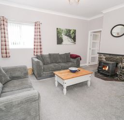 A living room with a sofa, armchair, coffee table, and fireplace at Dyffryn Bach in Glan-yr-afon near Corwen