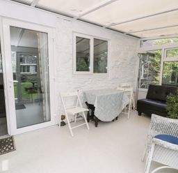 A conservatory with a table and chairs at Dyffryn Bach in Glan-yr-afon near Corwen