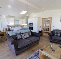 An open plan living room with sofas a wooden dining table and a kitchen at Squirrel Lodge in Gargrave near Skipton