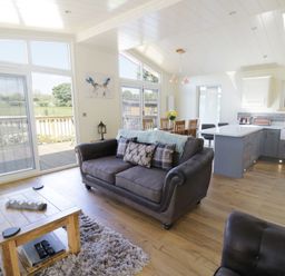 An open plan living room and kitchen with a sofa wooden dining table and kitchen island at Squirrel Lodge in Gargrave near Skipton
