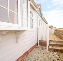 An exterior side pathway with gravel and steps next to a white house and stone wall at 11 Pendarves St Merryn near Padstow