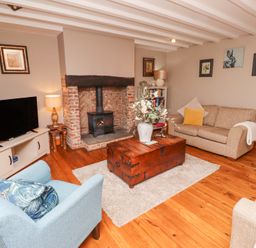 A living room with sofas a wooden chest table a fireplace and a television at Edendale in Longframlington near Alnwick