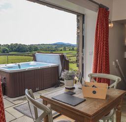 A seating area with a hot tub and view of the landscape at Acorn in Bowness-on-Windermere