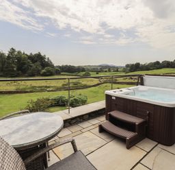 An outdoor area with a hot tub and seating at Acorn in Bowness-on-Windermere