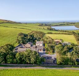 An aerial view of a property surrounded by fields and a lake at Ash Lodge in Pennington near Ulverston