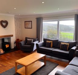 A living room with a fireplace and furniture at Rhos Helyg in Penysarn near Amlwch
