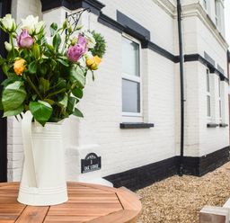 A vase with flowers on a wooden table outside a white brick house at Oak Lodge East Runton