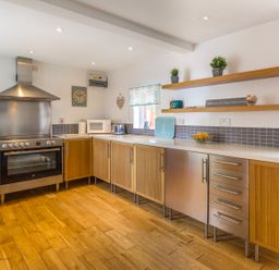 A kitchen with wooden cabinets stainless steel appliances and open shelves at Estuary View in Warkworth